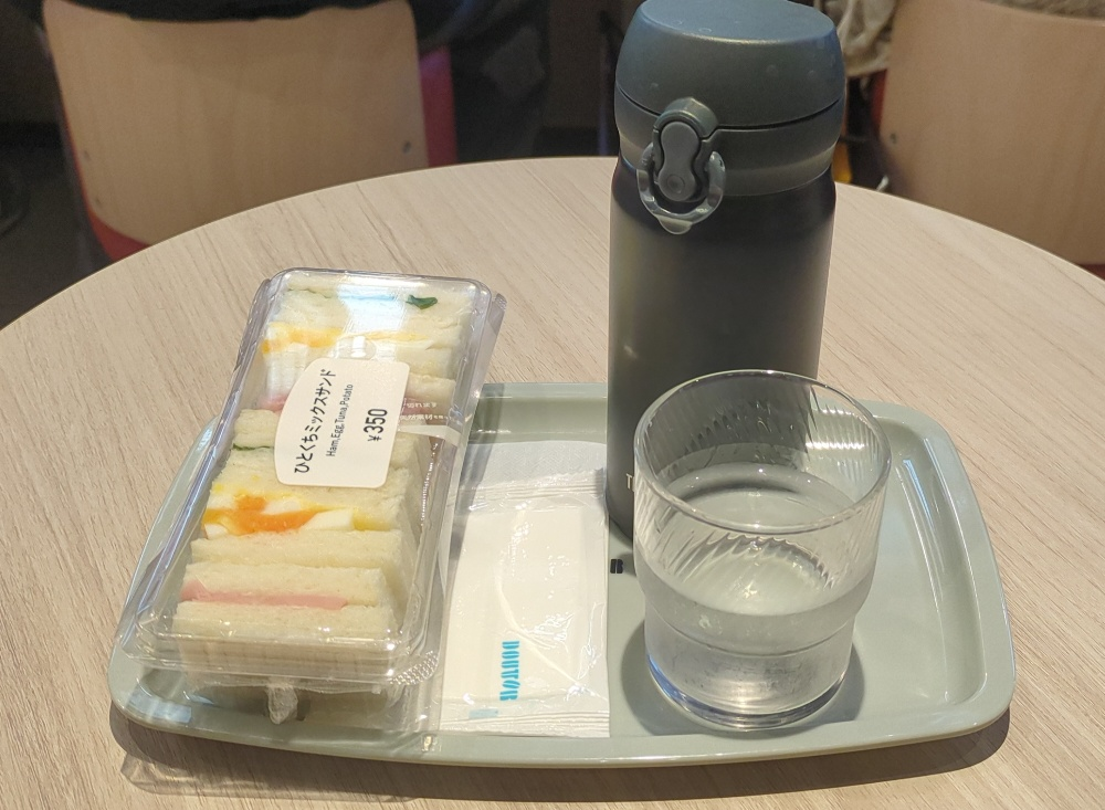 ドトールのトレー。ひとくちミックスサンド350円・タンブラー・お冷のグラスが並んでいる